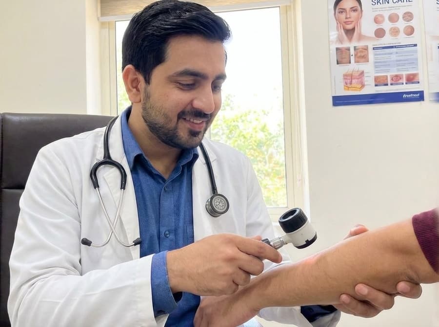 Dr. Raghvendra Pratap Singh examining a patient's skin with a dermatoscope